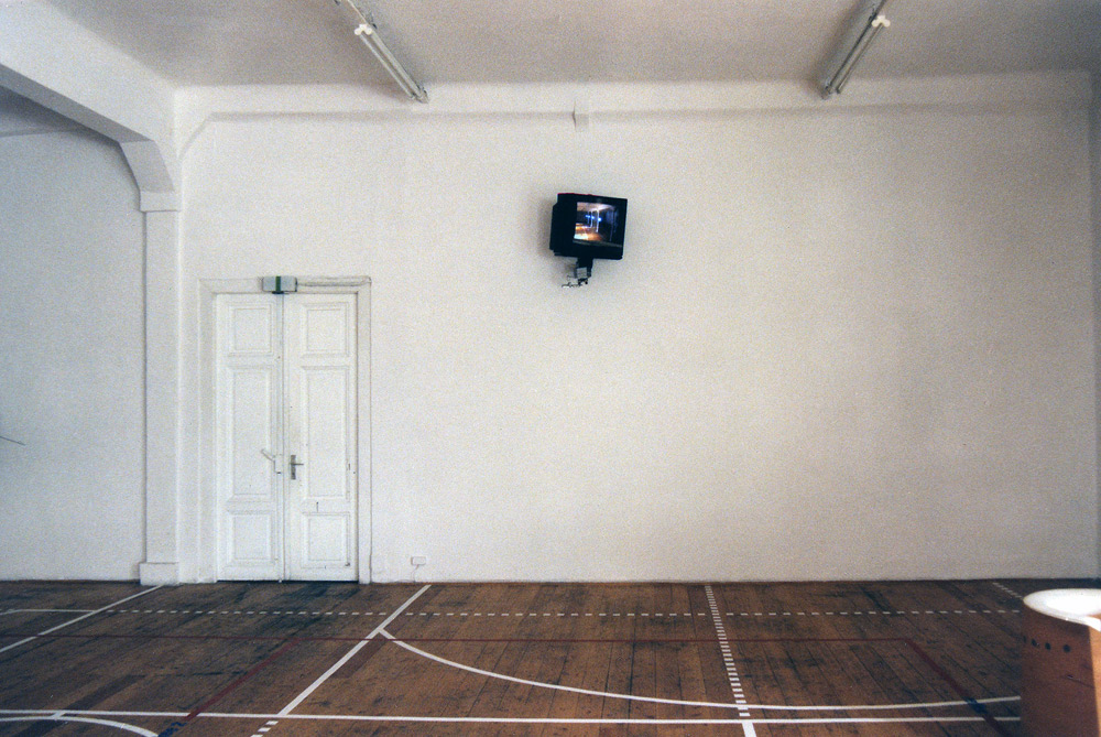 Art, artwork. An installation entitled "Reflex" by Nika Span / Nika Špan. Material: VHS player, VHS cassette (245 minutes), a video projector, a TV stand, a television set, a two-way mirror, an electric motor. Exhibition: SIQ 1999, WUK, Kunsthalle Exnergasse, Vienna, Austria.
