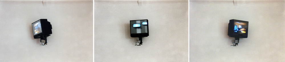 Art, artwork. An installation entitled "Reflex" by Nika Span / Nika Špan. Material: VHS player, VHS cassette (245 minutes), a video projector, a TV stand, a television set, a two-way mirror, an electric motor. Exhibition: SIQ 1999, WUK, Kunsthalle Exnergasse, Vienna, Austria. 